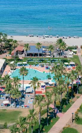 Vue aérienne du club Belambra Borgo Pineto avec sa piscine, ses palmiers et son accès direct à la plage.