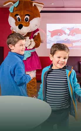 Petits garçons souriants devant Léa notre peluche renarde, mascotte Belambra aux clubs enfants