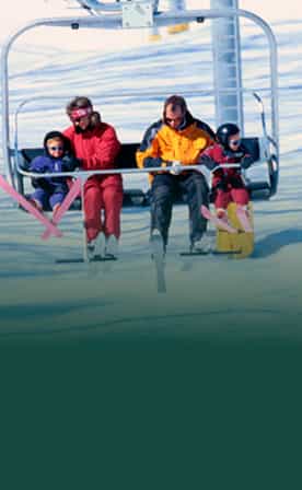 Personnes sur un télésiège en hiver dans une station de ski, portant des vêtements de ski colorés, avec de la neige en arrière-plan