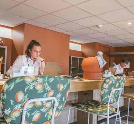 Espace bar et coworking du club Belgodère Belambra avec vacanciers installés en intérieur.