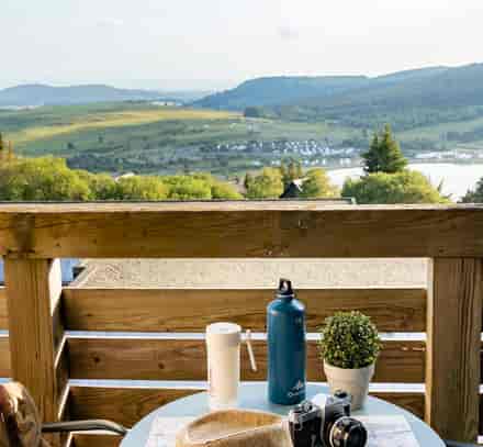 Balcon avec table de petit-déjeuner et vue sur le lac et les montagnes à Super-Besse.