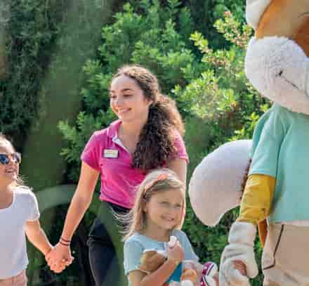 Animateur Belambra accompagnant des enfants aux côtés de la mascotte Léo pendant les activités du club.