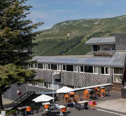 Bâtiment du club Belambra à Super-Besse avec terrasse et vue sur les montagnes en été.