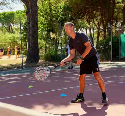 Un vacancier joue au tennis sur un court entouré de pins à La Grande-Motte.